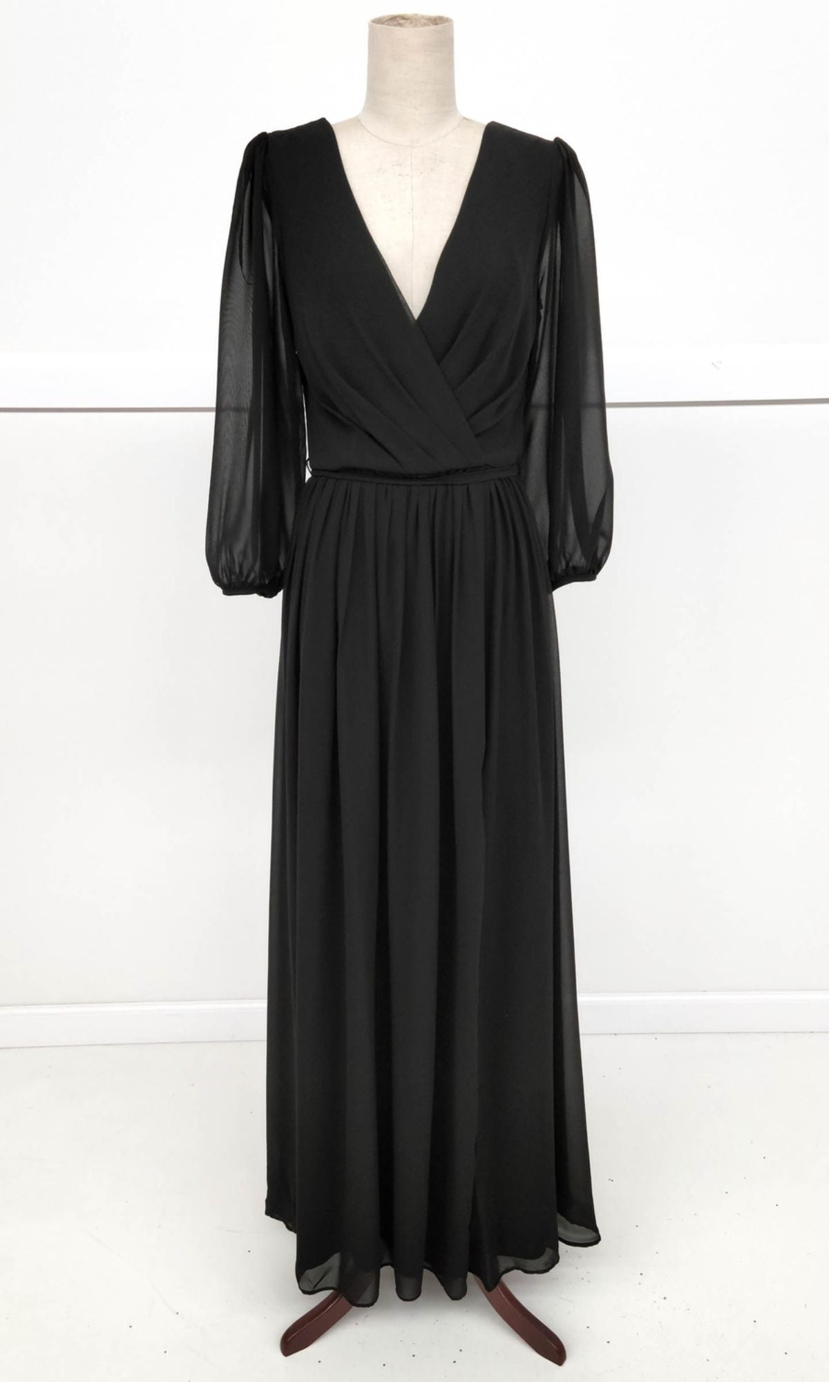 The Long-Sleeve Long Formal Dress: Chicas J012B, featuring a black V-neck wrap-style bodice and sheer sleeves, is displayed on a dress form against a plain white background.